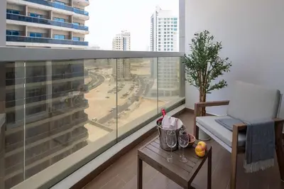 a balcony with a chair and a table and a large window at Frank Porter - Hera Tower in Dubai