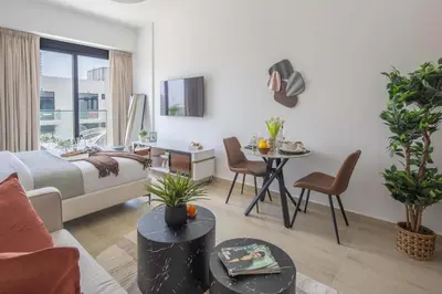 a living room with a bed and a table with chairs at Frank Porter - Elysee III by Pantheon, JVC in Dubai