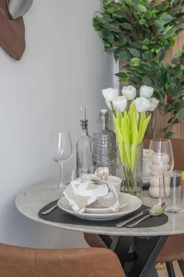 a table with plates and glasses and a vase of flowers at Frank Porter - Elysee III by Pantheon, JVC in Dubai