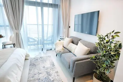 a living room with a couch and a tv at Cozy Studio, All Bills Included in Dubai
