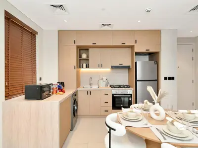 a kitchen with a table and a stove and refrigerator at Elegant 2BR Apartment in Socio Tower - Dubai Hills in Dubai