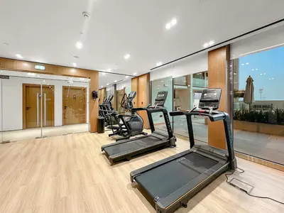 a gym with several treadmills and elliptical machines at FIRST CLASS Studio Cozy Hideaway in Dubai