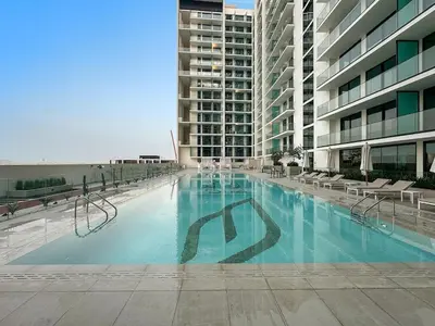 a large swimming pool with chairs and a building at FIRST CLASS Studio Cozy Hideaway in Dubai
