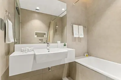 a white bathroom with a sink and a tub at Spacious 1BR for 2, 10 Min Meydan Racecourse, Pool & Gym Access in Dubai