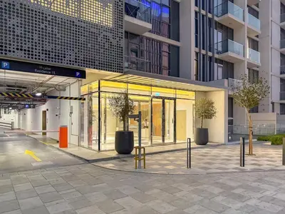 a building with glass doors and trees in front of it at Spacious 1BR for 2, 10 Min Meydan Racecourse, Pool & Gym Access in Dubai