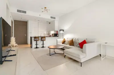 a living room with a white couch and a table at Spacious 1BR for 2, 10 Min Meydan Racecourse, Pool & Gym Access in Dubai