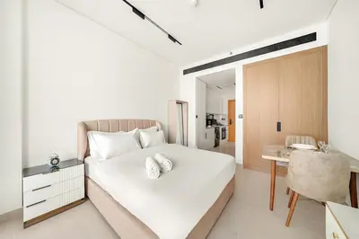 a white bedroom with a bed and a desk at FIRST CLASS Studio Cozy Luxury Escape in Dubai