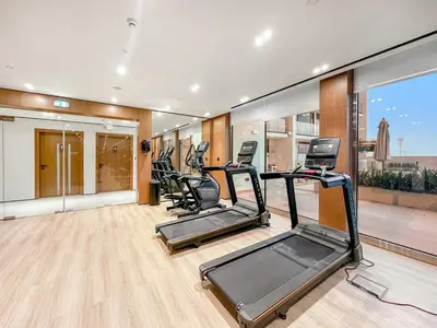 a gym with treadmills and ellipticals in a room at FIRST CLASS Studio Cozy Luxury Escape in Dubai