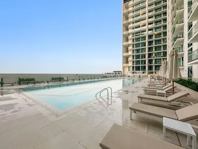 a swimming pool with chairs and umbrellas next to a building at FIRST CLASS Studio Cozy Luxury Escape in Dubai