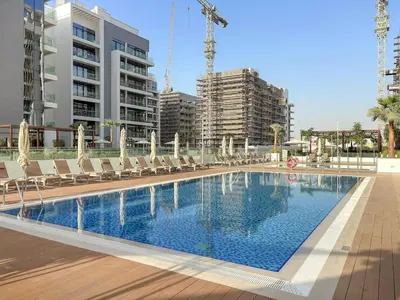 a large swimming pool with lounge chairs and buildings at FIRST CLASS Studio Luxury Comfort , Pool View in Dubai
