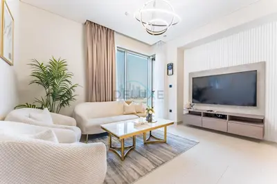 a living room with a tv and a couch and a table at Modern Apartment Near Sobha Hartland Amenities, Minutes from Ras Al Khor Wildlife Sanctuary and Downtown Dubai, Sobha Creek Vistas Tower A, Sobha Hartland by Deluxe Holiday Homes in Dubai