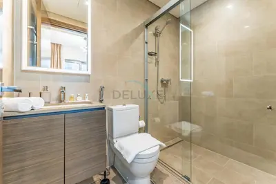 a bathroom with a toilet and a glass shower at Modern Apartment Near Sobha Hartland Amenities, Minutes from Ras Al Khor Wildlife Sanctuary and Downtown Dubai, Sobha Creek Vistas Tower A, Sobha Hartland by Deluxe Holiday Homes in Dubai