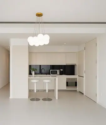 a white kitchen with a table and two stools at Index Tower DIFC with Burj Khalifa View Chic 1 BR in Dubai
