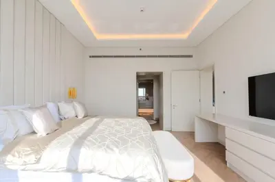 a white bedroom with a bed and a flat screen tv at Daniels 1BR with Sea View at The Palm Tower in Dubai