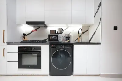 a white kitchen with a washing machine and a stove at Luxury Trillionaire Studio with Jacuzzi and Canal Views in Business Bay in Dubai