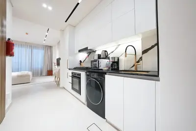 a white kitchen with a washer and dryer at Luxury Trillionaire Studio with Jacuzzi and Canal Views in Business Bay in Dubai