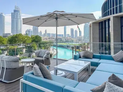 a patio with blue couches and an umbrella at Seraya Residences at Address Opera Dubai in Dubai