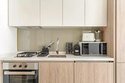 a kitchen with white cabinets and a stove and microwave at VayK - Elegant Canal View studio in Business Bay in Dubai