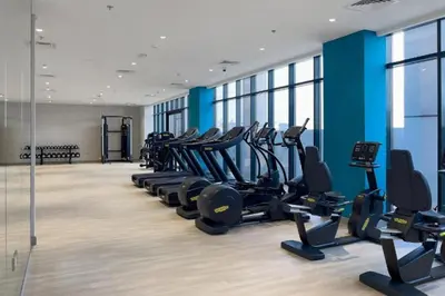 a gym with a row of treadmills and ellipticals at Locations l Luxurious Studio l Free Pool, Gym Access l Meydan in Dubai