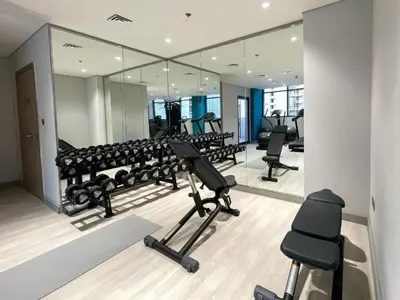 a gym with several treadmills and mirrors at Locations l Luxurious Studio l Free Pool, Gym Access l Meydan in Dubai
