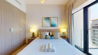 a bedroom with a large white bed with two towels at Locations l Luxurious Studio l Free Pool, Gym Access l Meydan in Dubai