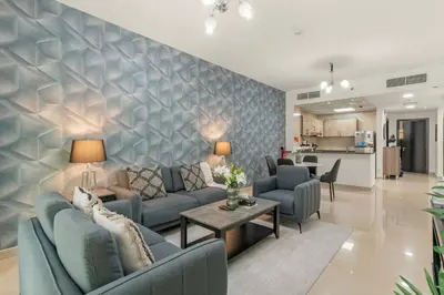 a living room with blue couches and a kitchen at Charming 1BR with Balcony and City View in JVC in Dubai