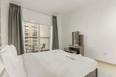 a bedroom with two white beds and a large window at Charming 1BR with Balcony and City View in JVC in Dubai