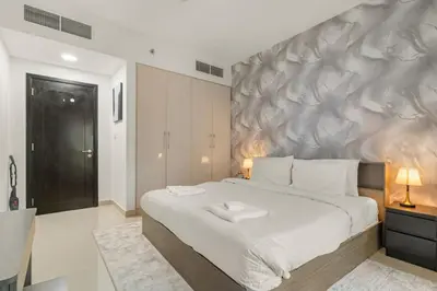 a bedroom with a large white bed and a wall at Charming 1BR with Balcony and City View in JVC in Dubai