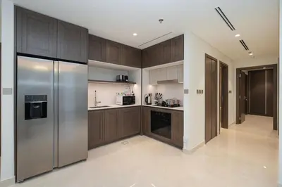 a kitchen with wooden cabinets and a stainless steel refrigerator at Beach access 2BR with Balcony & Sea View in Dubai