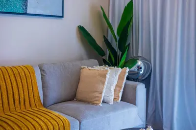 a couch with a yellow throw pillow in a living room at 1Bedroom Canal View near Dubai Mall-Business Bay in Dubai
