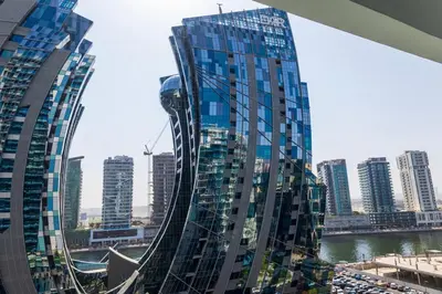 a view of a tall glass building in a city at 1Bedroom Canal View near Dubai Mall-Business Bay in Dubai