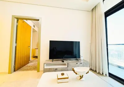 a living room with a television and a large window at Dream Shoma- Experience Luxury Living 2BR APT in Dubai