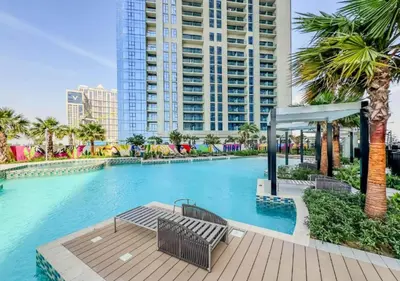 a large swimming pool with palm trees and a building at Dream Shoma- Experience Luxury Living 2BR APT in Dubai