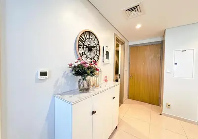 a room with a clock on the wall and a vase of flowers at Dream Shoma- Experience Luxury Living 2BR APT in Dubai