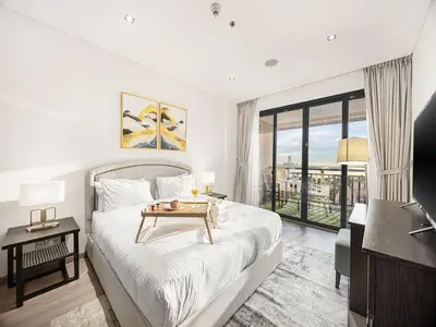 a white bedroom with a bed and a balcony at Livin' Holidays - 1 BR - Anantara Lagoon Stay in Dubai