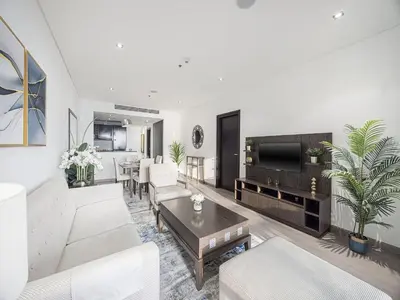 a living room with white furniture and a flat screen tv at Livin' Holidays - 1 BR - Anantara Lagoon Stay in Dubai