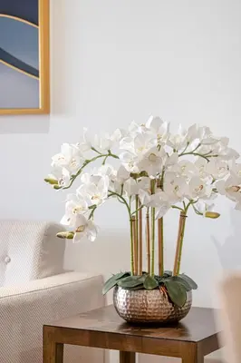 a vase filled with white flowers on a table at Livin' Holidays - 1 BR - Anantara Lagoon Stay in Dubai
