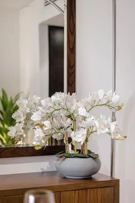 a vase filled with white flowers sitting on a table at Livin' Holidays - 1 BR - Anantara Lagoon Stay in Dubai