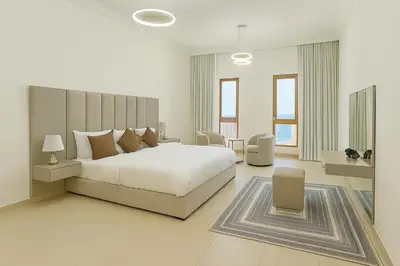 a white bedroom with a large bed and chairs at Sunset Beach Escape at Palm Jumeirah 2BR 241 by The Rosewood Vacation Homes Rental LLC in Dubai