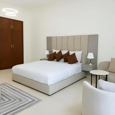a white bedroom with a large bed and a chair at Sunset Beach Escape at Palm Jumeirah 2BR 241 by The Rosewood Vacation Homes Rental LLC in Dubai