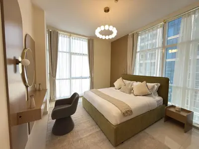 a bedroom with a bed with a chair and windows at Duja Tower 4114 in Dubai