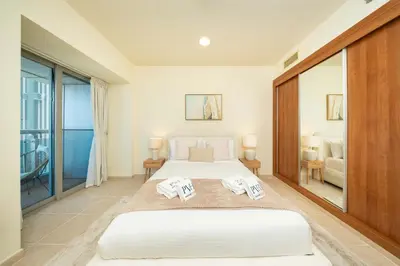 a bedroom with two beds and a balcony at PVH - Sea View 3BR and Maids Room - Princess Tower in Dubai