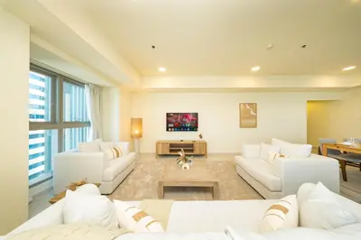 a living room with white couches and a tv at PVH - Sea View 3BR and Maids Room - Princess Tower in Dubai