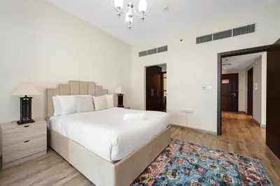 a white bedroom with a large bed and a rug at Modern 1BR I Canal View I Business Bay Dubai in Dubai