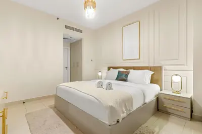 a white bedroom with a large white bed with two animals on it at FIRST CLASS 1BR Burj Khalifa View , Near Metro in Dubai