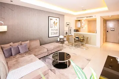 a living room with a couch and a dining room at Modern 1BHK With World Class Amenities at Paramount Tower in Dubai