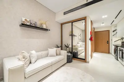 a living room with a white couch and a kitchen at FIRST CLASS Studio Canal and Pool View in Dubai