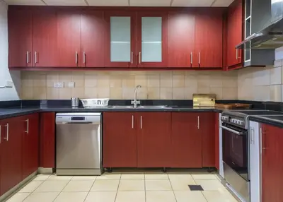 a kitchen with red cabinets and a sink at Rimal 1 JBR Beach Access 3 BR in Dubai