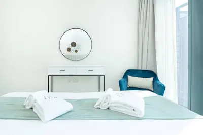 a bedroom with a bed with a blue chair and a mirror at PVH - Vibrant 1BR near Dubai Opera - BLVD Heights in Dubai