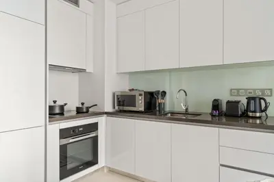 a white kitchen with white cabinets and appliances at FIRST CLASS 1BR Cozy Luxe Escape in Dubai